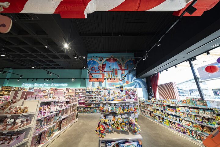 Zona de primera infancia y mu&ntilde;ecos beb&eacute; bajo el mural decorativo en la tienda de juguetes de Puerto Venecia Abracadabra